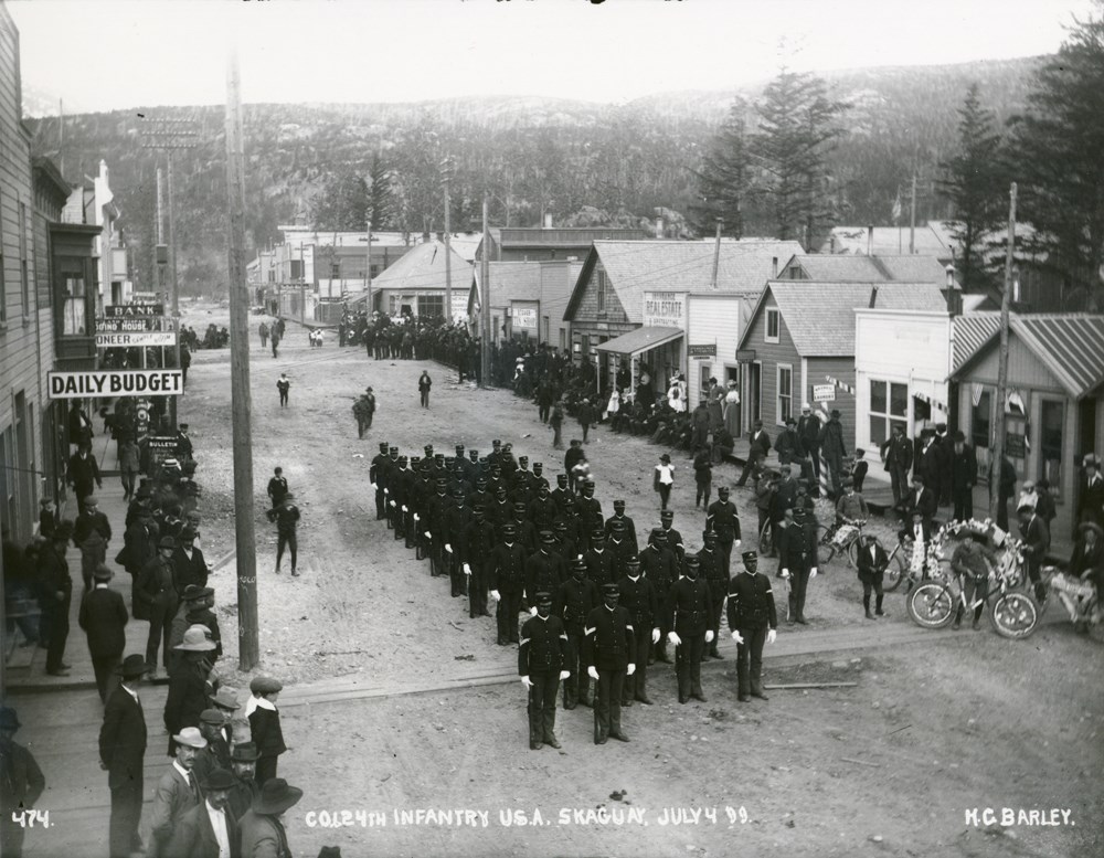 Historic photo of soldiers in a street with people looking on from the sides