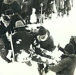 Historic black and white photo of men lifting a frozen body