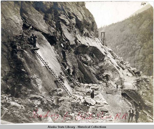 men working to build a railroad on the side of a steep mountain