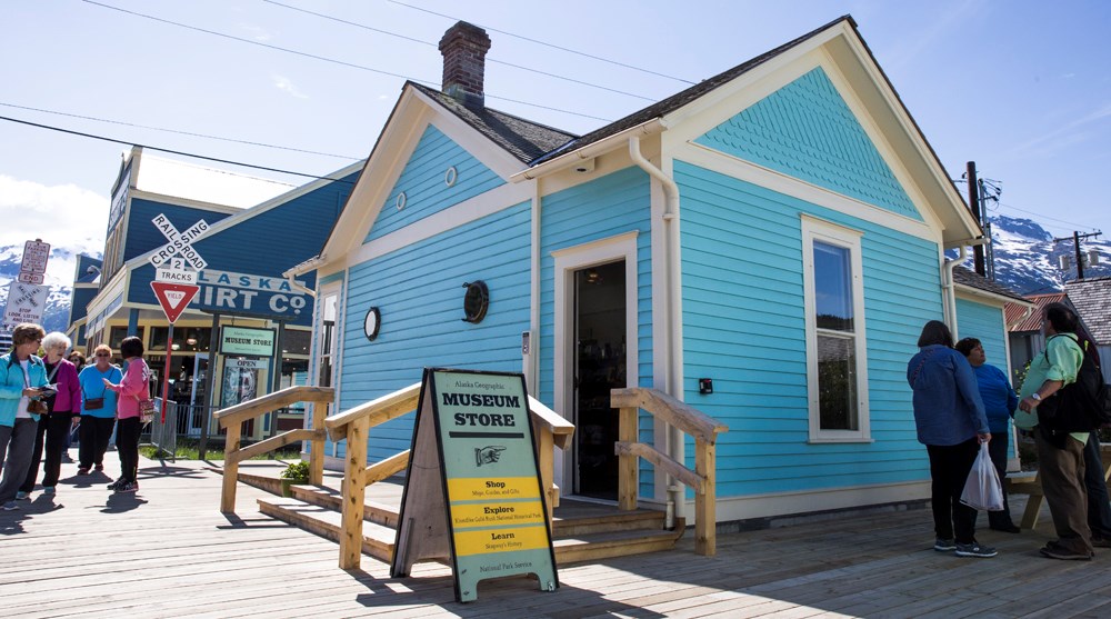 People on boardwalk near blue building with sign "Museum Store" People on boardwalk near blue building with sign "Museum Store"