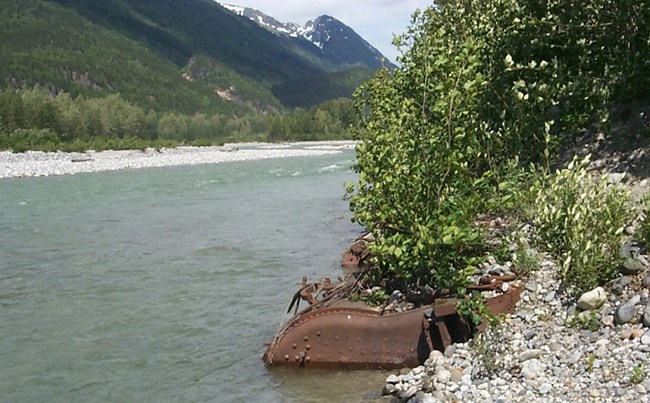 Large rusted metal embedded at edge of river Large rusted metal embedded at edge of river