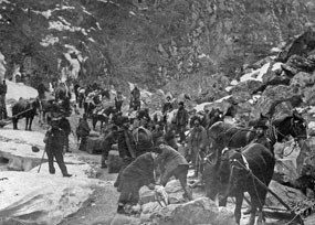 Black and white photo of men and horses standing in a canyon Black and white photo of men and horses standing in a canyon