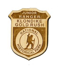 Wooden badge with text "Junior Ranger Klondike Gold Rush National Historical Park"