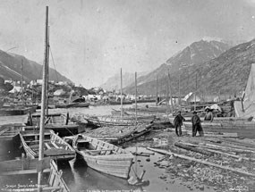 Black and white photo of wooden boats line the edge of water. Black and white photo of wooden boats line the edge of water.