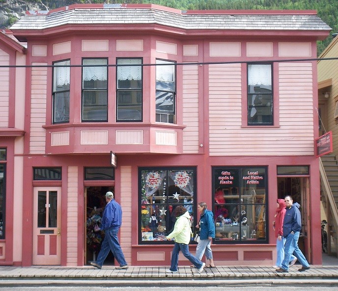 Two colorful buildings with people passing by.