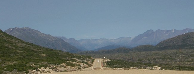 A dirt road in a valley edged by mountains A dirt road in a valley edged by mountains