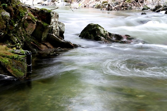 Scientific equpiment sits along the bank of a stream