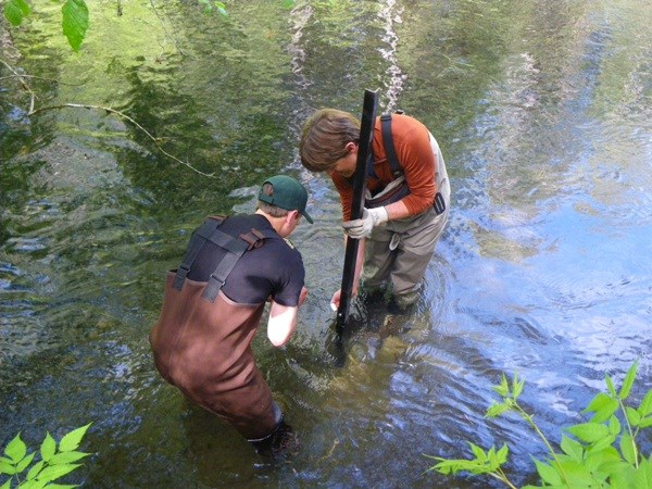 Two people standing in water with scientific equipment