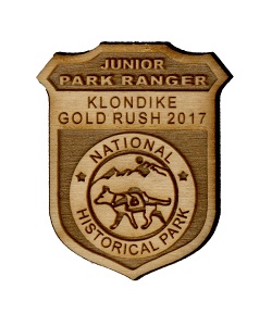 Wooden badge with dog carrying a pack reading junior park ranger Klondike Gold Rush 2017 National Historical Park