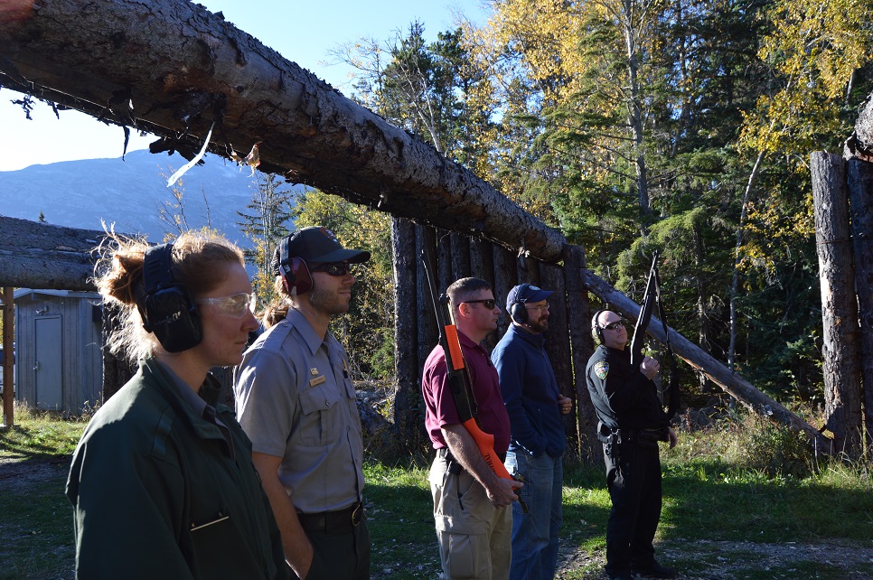 Five people with ear protection and guns stand outside