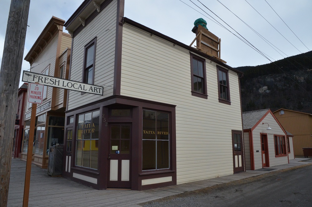 Brown and white two story building with sign "Fresh Local Art"