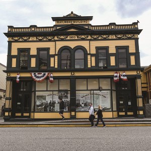 The Administration building decorated for the 4th of July, with people walking by and a crow perched on the top right.