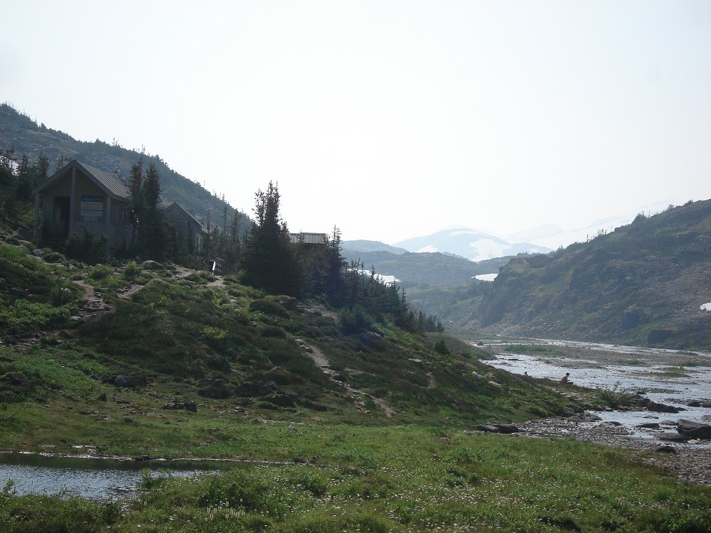 Small buildings on low hill by water in mountain valley Small buildings on low hill by water in mountain valley