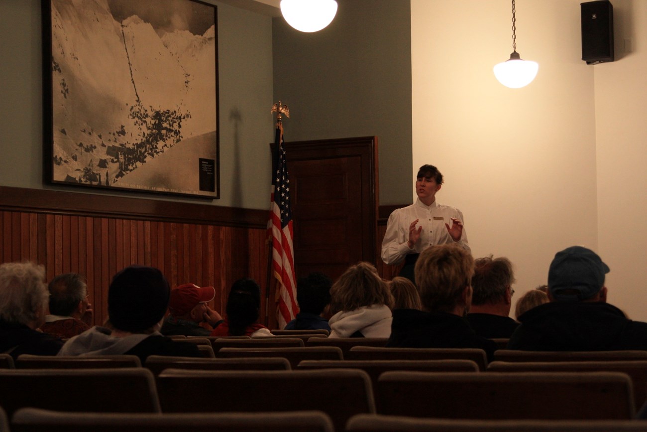 A person in historic clothing talks to people in an auditorium