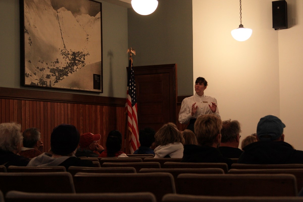 A person in historic clothing talks to people in an auditorium A person in historic clothing talks to people in an auditorium