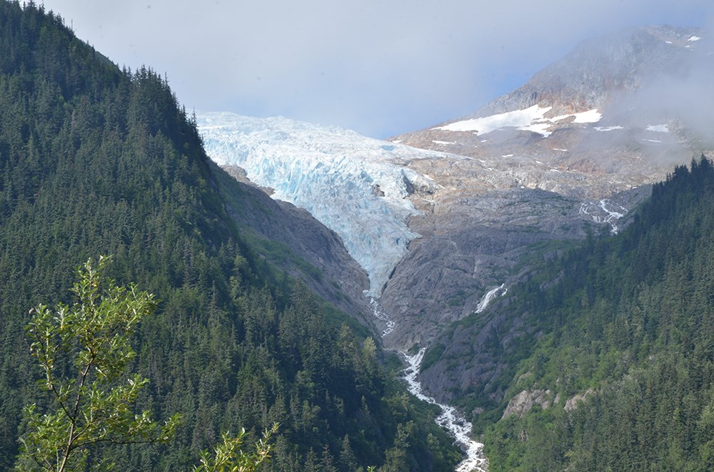 A hanging glacier in a mountain valley with a waterfall from the bottom.