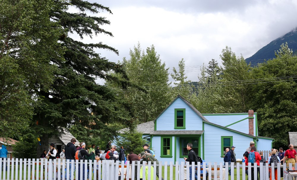 Crowd of people in the yard in front of a bright blue house