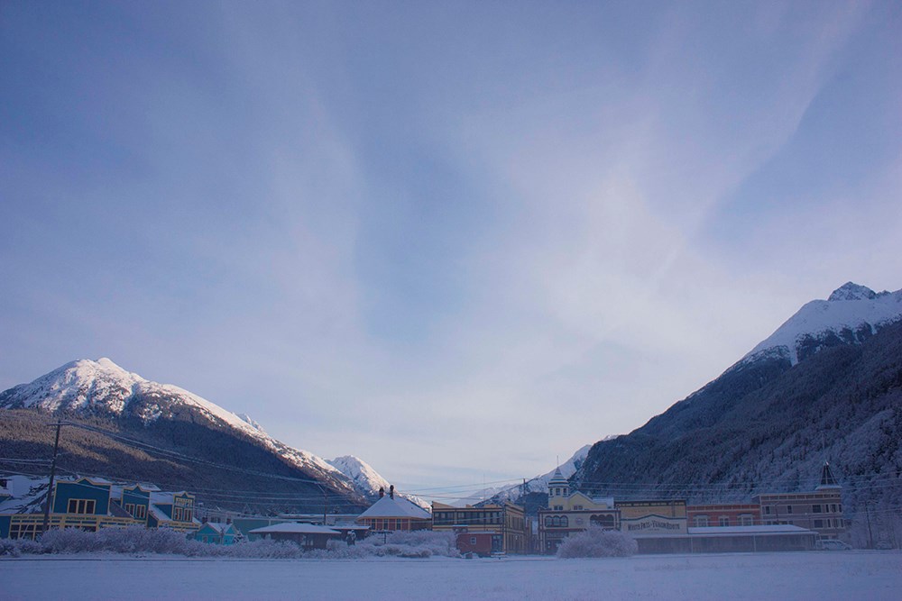 Colorful town buildings in a snowy landscape dwarfed by a large blue sky