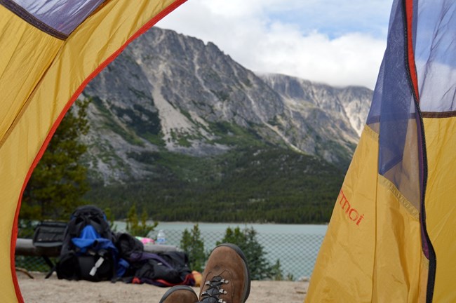 Looking out of a tent toward mountains and a lake Looking out of a tent toward mountains and a lake