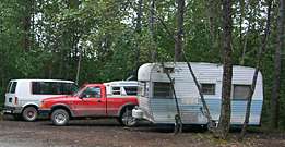 Vehicles and a camper parked in the forest Vehicles and a camper parked in the forest