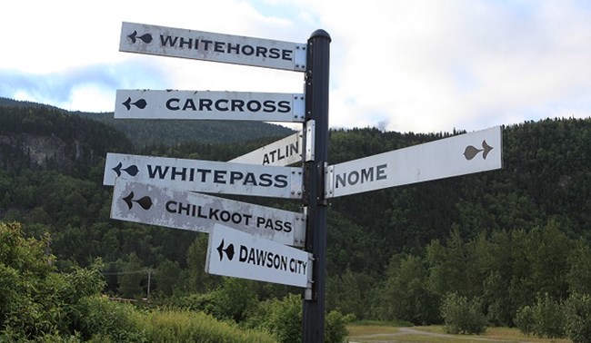 Multiple signs on a pole point in the directions of gold rush destinations Multiple signs on a pole point in the directions of gold rush destinations