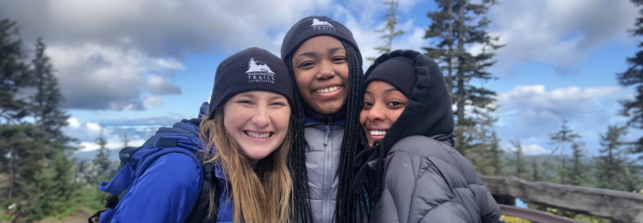 Three people smiling wearing hats.