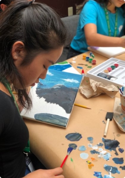 Person mixing paint swatches with a paintbrush on a table.