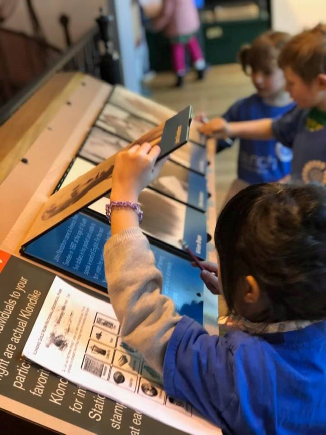 in museum kids look at an exhibit with flip up lids revealing cards underneath