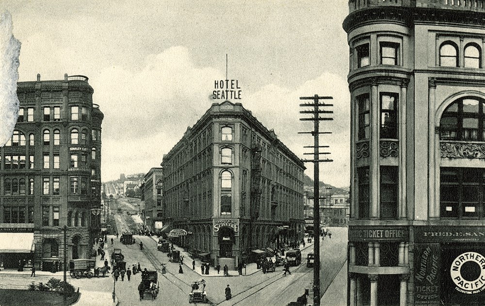 A black and white postcard image of a triangle shaped building between two streets.