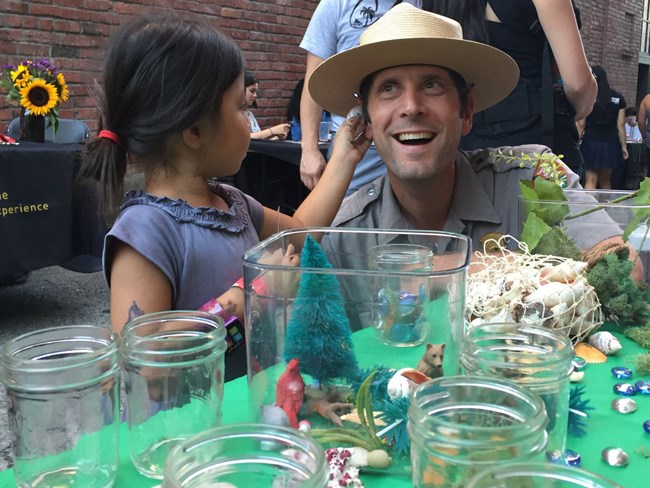 Ranger at a community event listening to a child holding a seashell