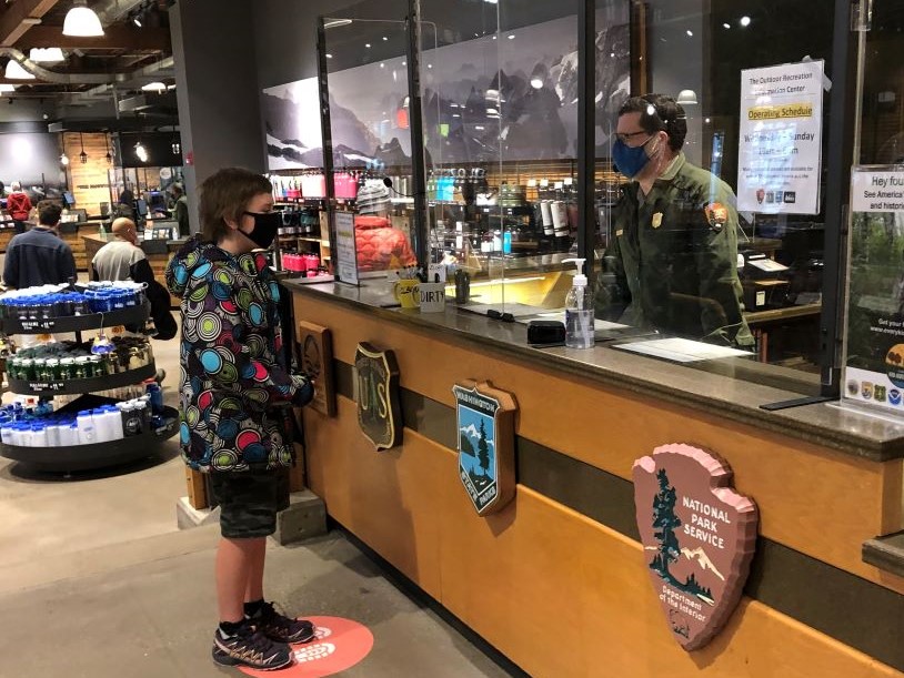 A park ranger talks with a person through Plexiglass