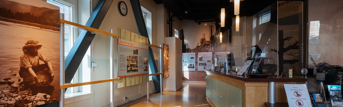 Historical photographs, exhibits and a large desk topped with plexiglass inside a museum.