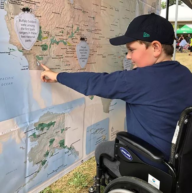 A person sitting in a wheelchair pointing to a map