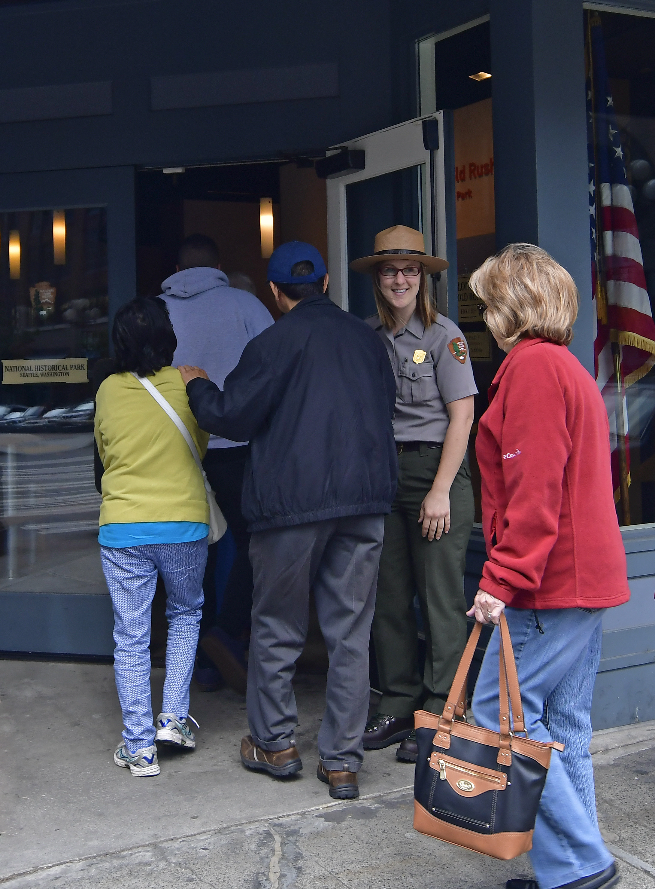 Ranger holding open entry door for incoming visitors Ranger holding open entry door for incoming visitors