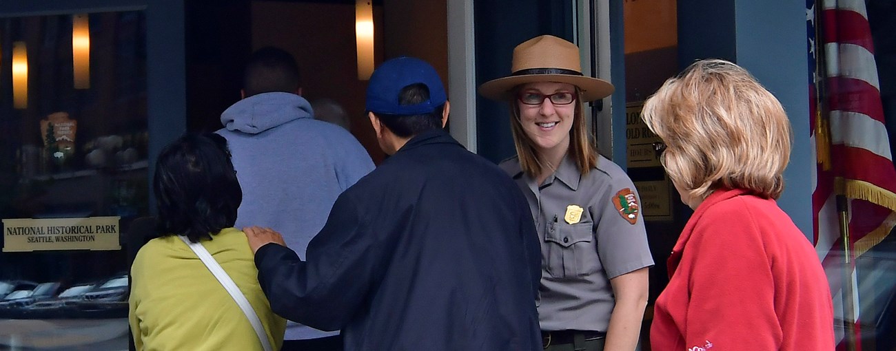 Ranger in uniform speaking to a group of visitors.