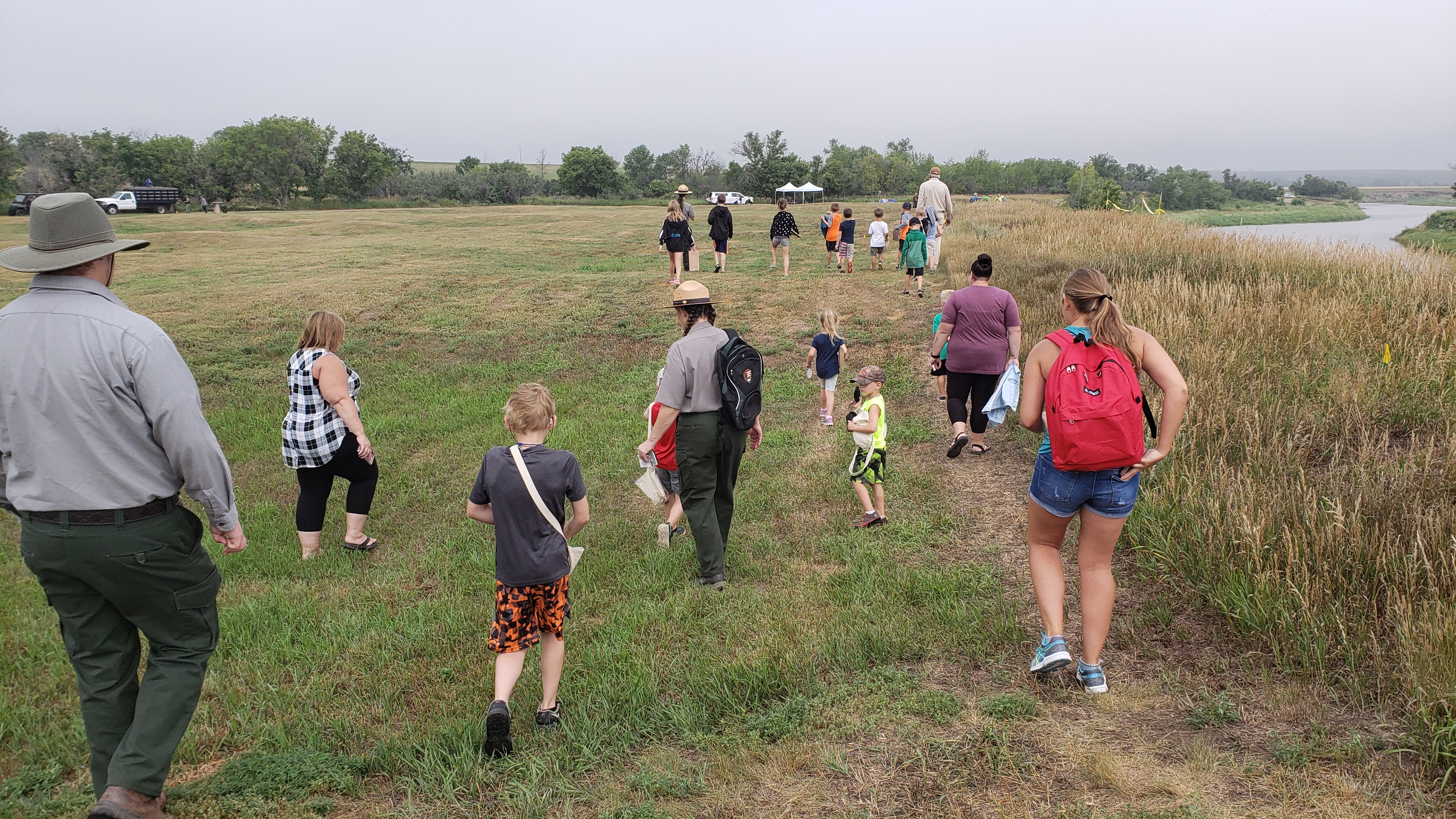 Kids, teachers, and rangers walk toward archeology site.