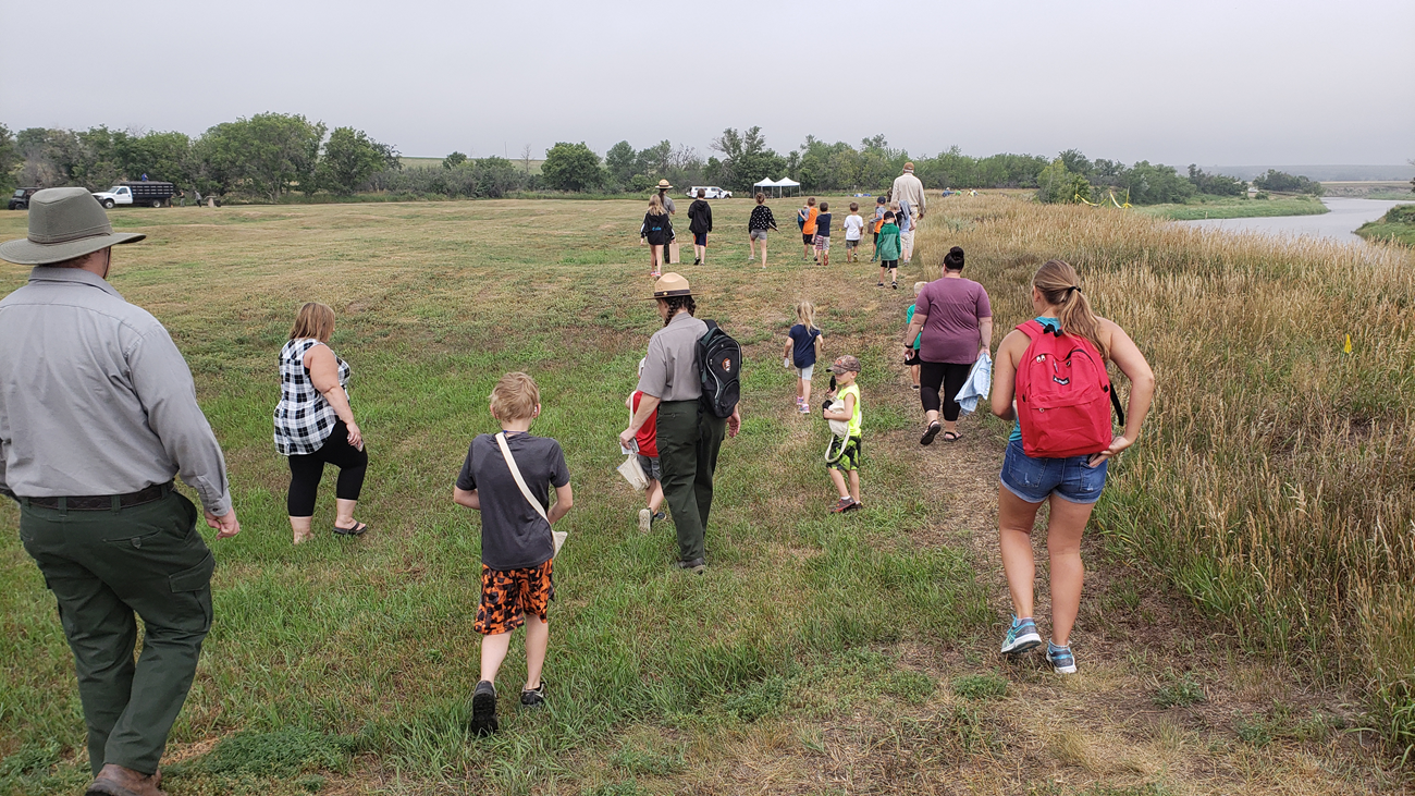 Kids, teachers, and rangers walk toward archeology site. Kids, teachers, and rangers walk toward archeology site.