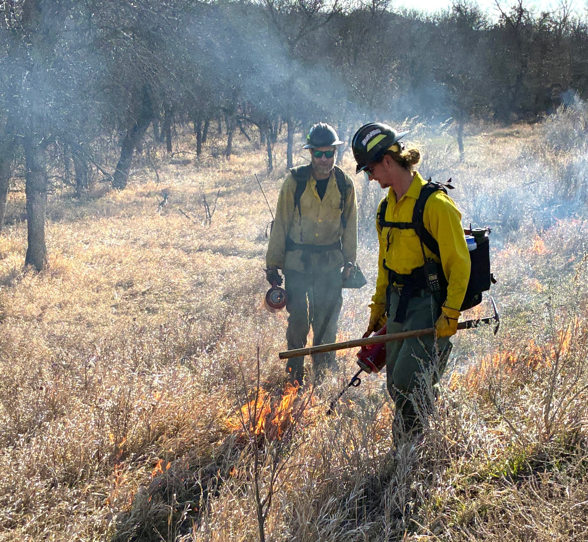 Two firefighters put fire on the landscape