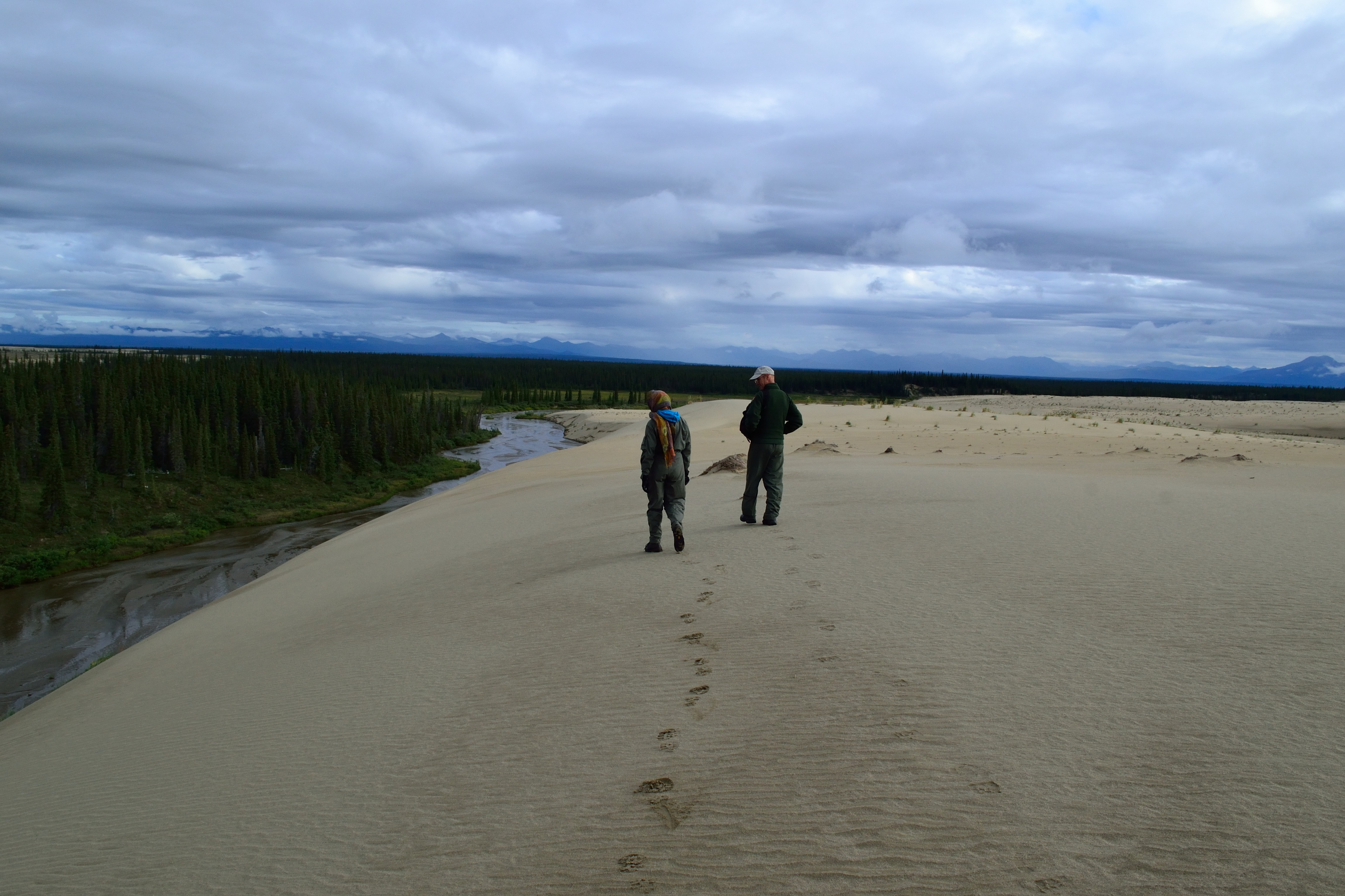 NPS Ranger, Thea, and an NPS Pilot, Rick, hike along a dune in the Great Kobuk Sand Dunes while wearing their Nomex flight suits. Photo by NPS/Rachel Post.
