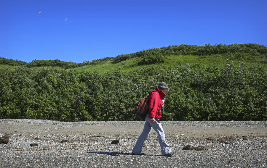 woman in red jacket walking along beach