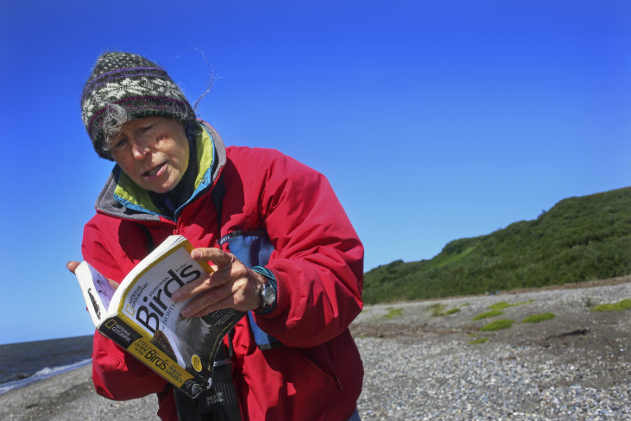 woman in red jacket looking at bird book