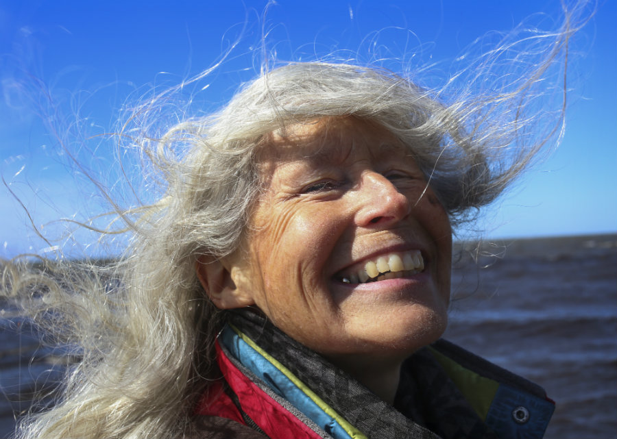 woman with white hair smiling in front of the ocean
