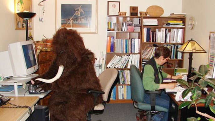 Woman and person in a mammoth costume working in an office