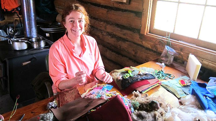 Woman sewing at a table covered in fabric scraps