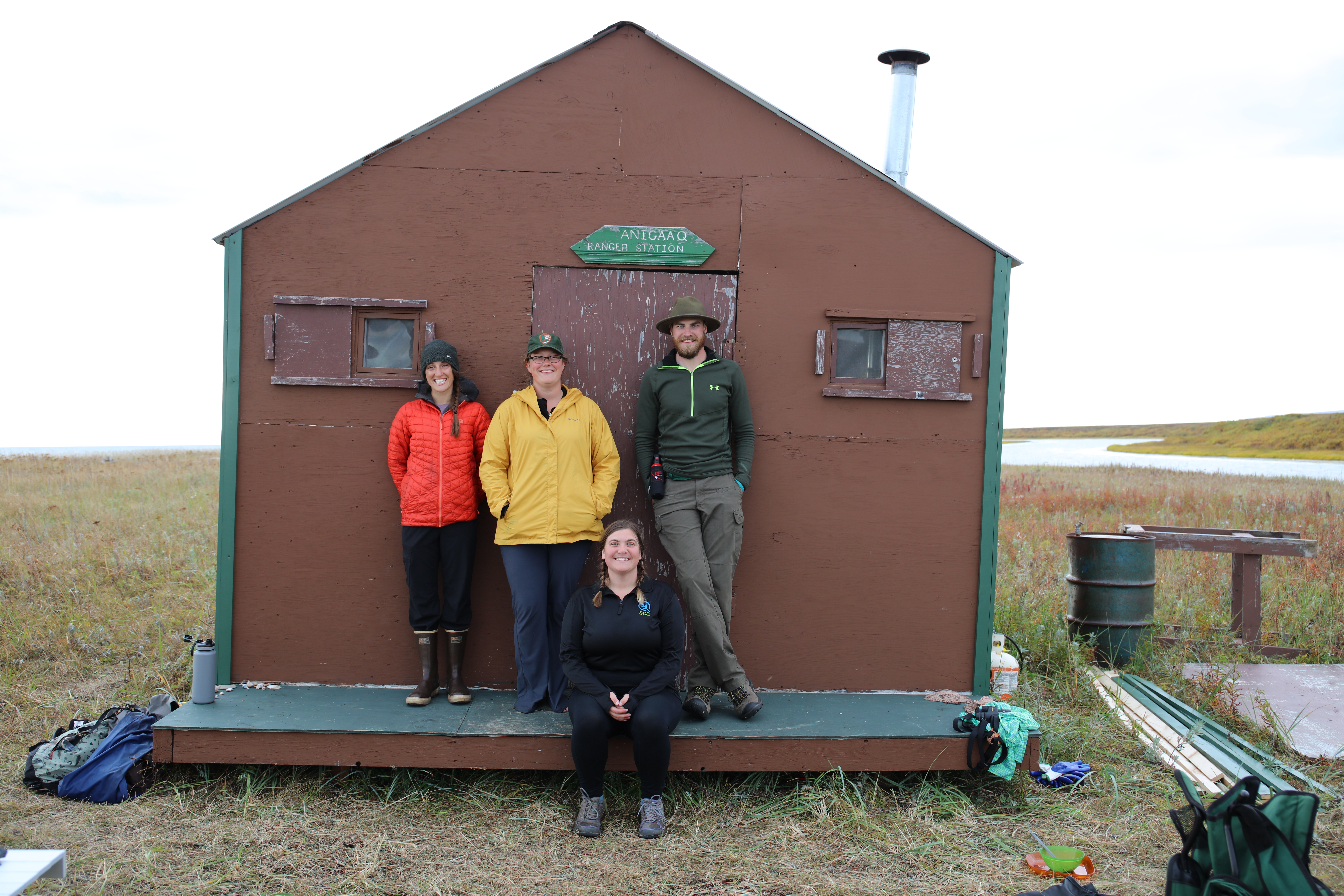 A group of four park rangers stand in front of a cabin