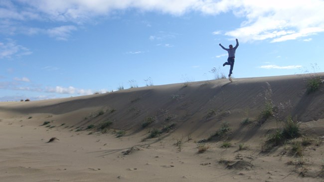 girl jumping on sand dune