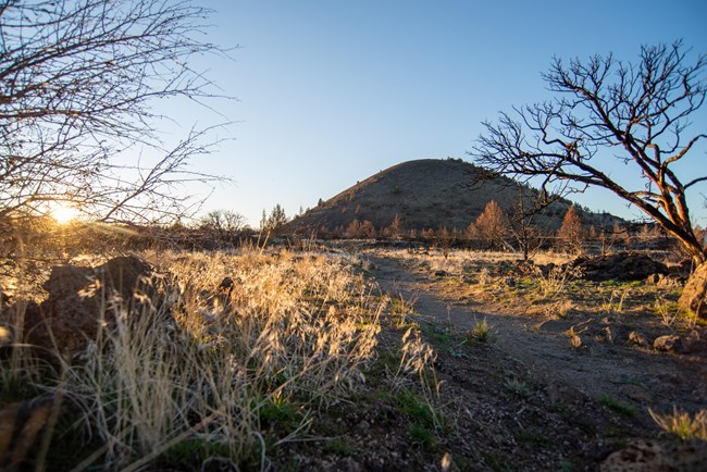 A trail winding off into the distance at sunset with Schonchin Butte in the background.