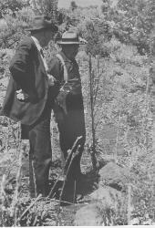 A historical image of two men in hats talking on a trail