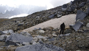 man walking on a rocky hillside near a patch of snow man walking on a rocky hillside near a patch of snow