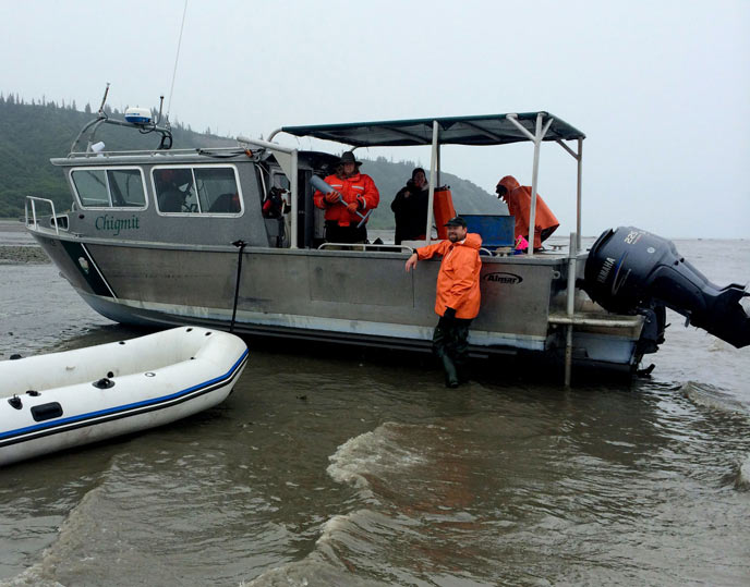 people in rain gear standing on a metal boat with a raft nearby people in rain gear standing on a metal boat with a raft nearby
